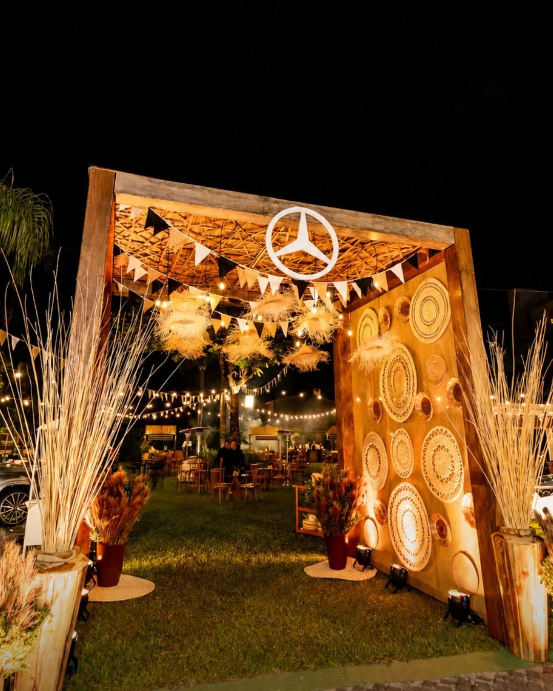 Decoración de evento corporativo Mercedes-Benz: arco de madera iluminado con guirnaldas y panel de fibras tejidas
